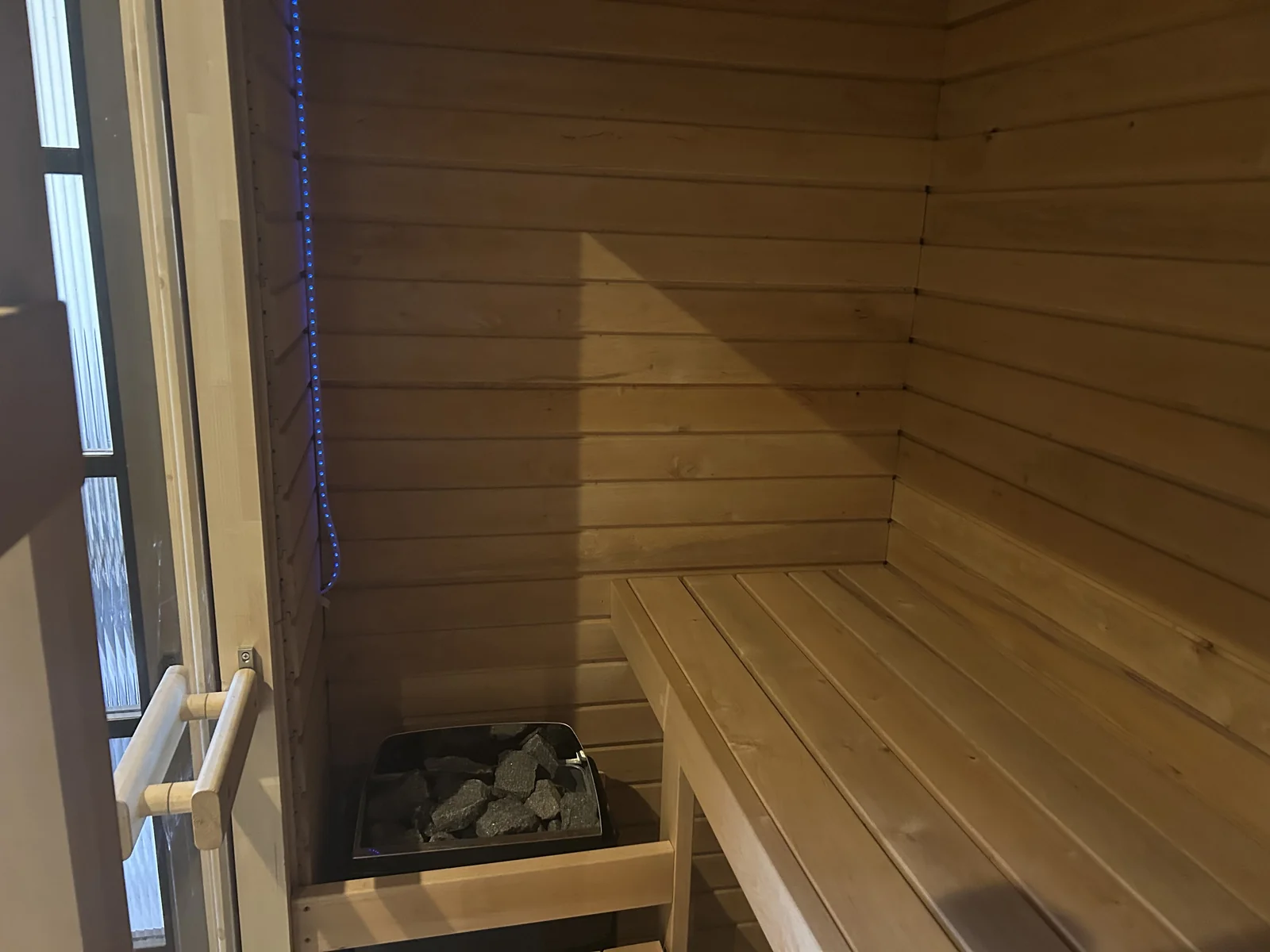 Interior of timber sauna with heater and benching