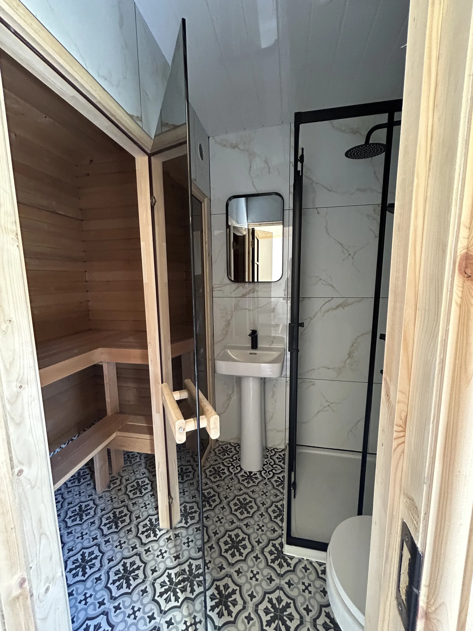 Sauna entrance next to bathroom with patterned floor tiling