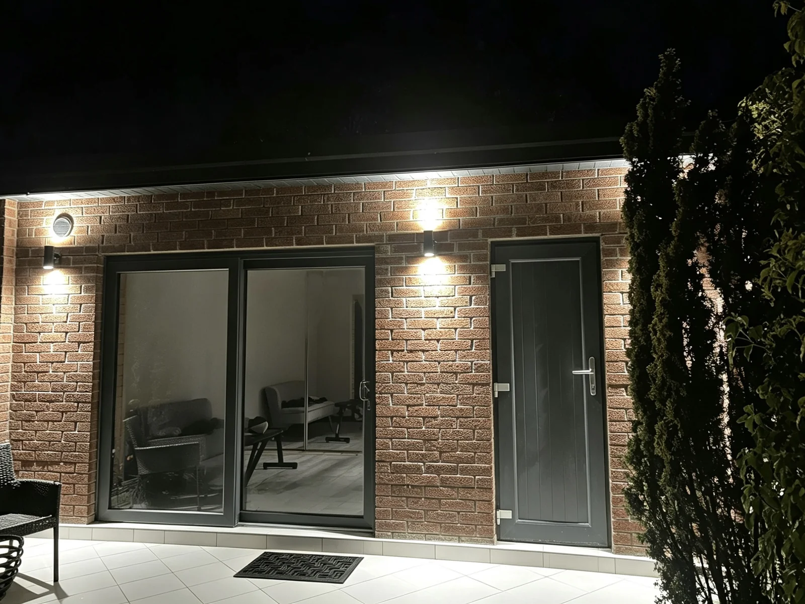 Garden room exterior at night with wall-mounted lighting