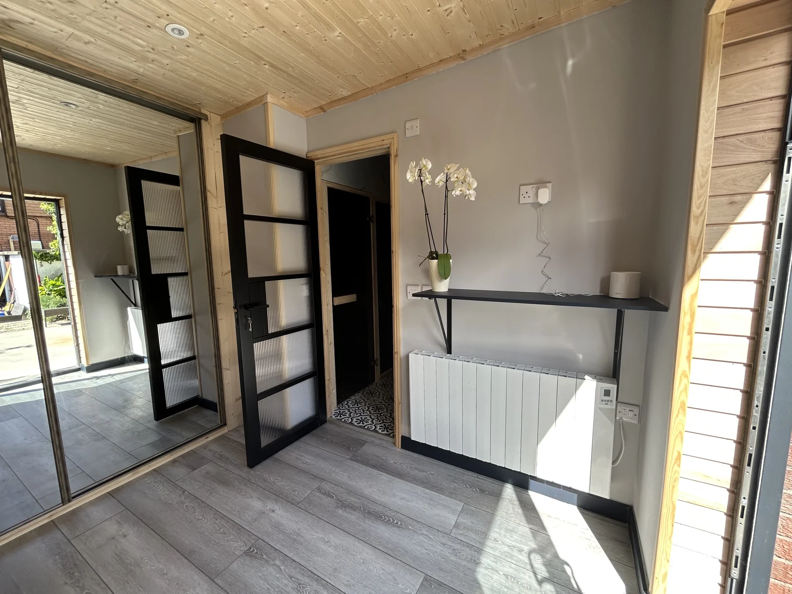 Bright interior of garden room with timber-clad ceiling and electric radiator